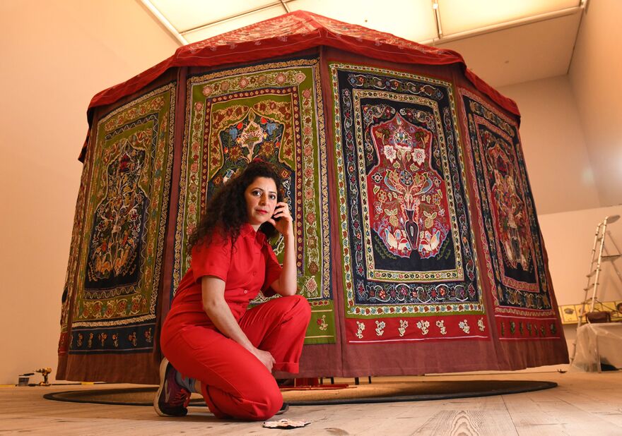 Artist Mounira in front of red embroidered tent