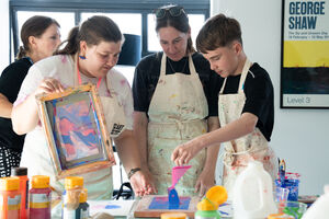 Three people making colourful riso prints together.