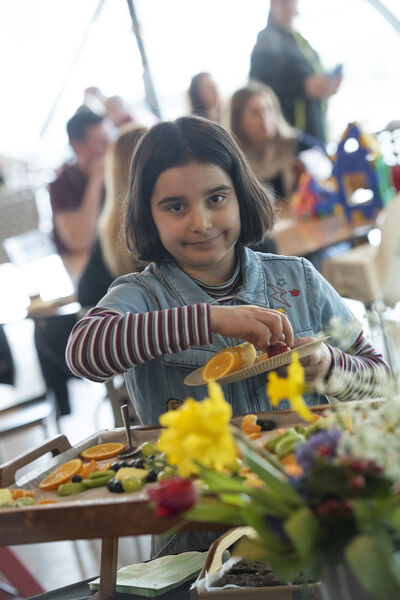 Girl smiling at the camera with a plate of colourful fruit.