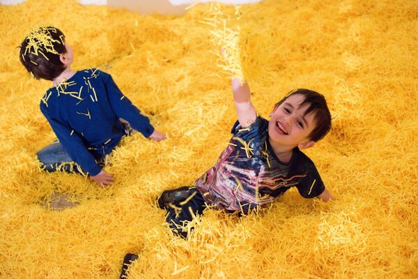 Kids playing in shredded yellow paper pit