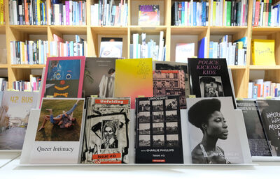 Stack of books infront of a bookshelf.