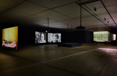 Room with five large screens suspended from the ceiling showing films.