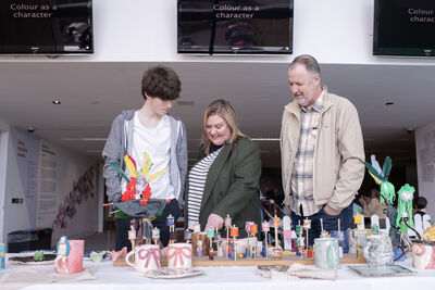 Three people stand admiring crafts on a table