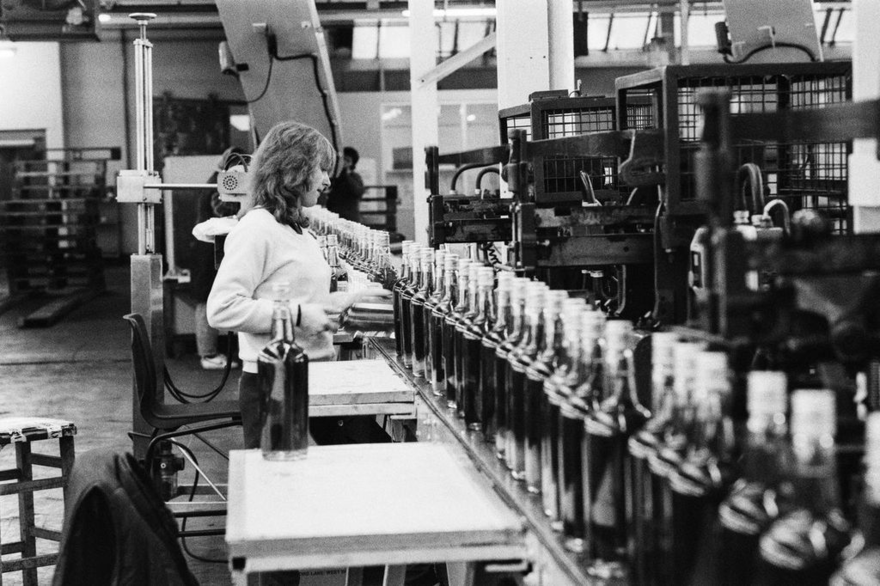 A woman looking at bottles in a factory