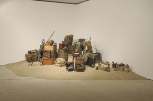 A pile of chests, barrels and explorers equipment on sand. 