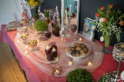 Table covered in pink tablecloth, flowers and sweet treats.