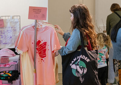 A person browses a rack of screen printed t-shirts.