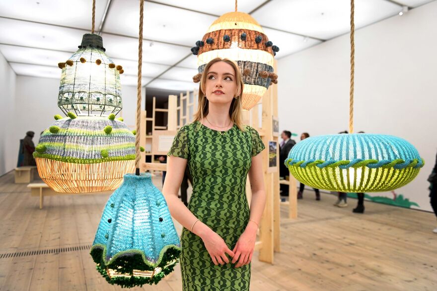 Person standing amongst lampshade artworks