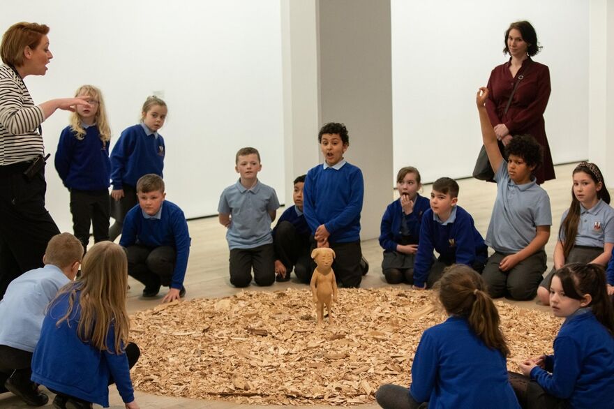 Children huddled around art made out of wood