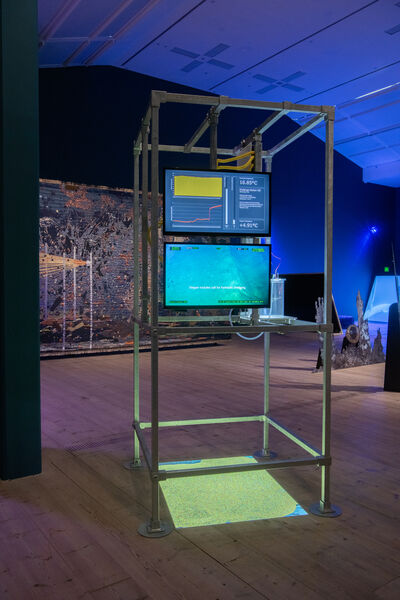 Two screens showing graphs and an underwater camera, displayed in a scaffolding structure.