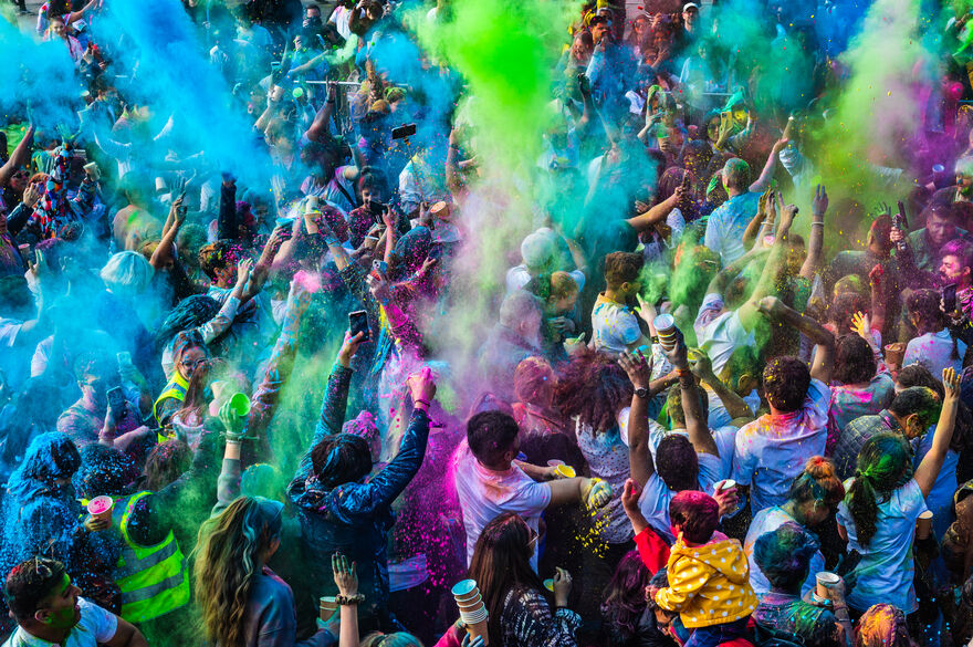 People stood in a crowd smiling and covered in colourful paint