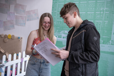 Two young people stand looking at a book