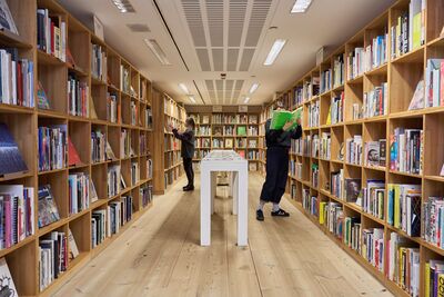 Two people in the library picking books off shelves