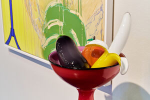 Colourful red glass bowl with glass fruit in it: a banana, aubergine and an orange.