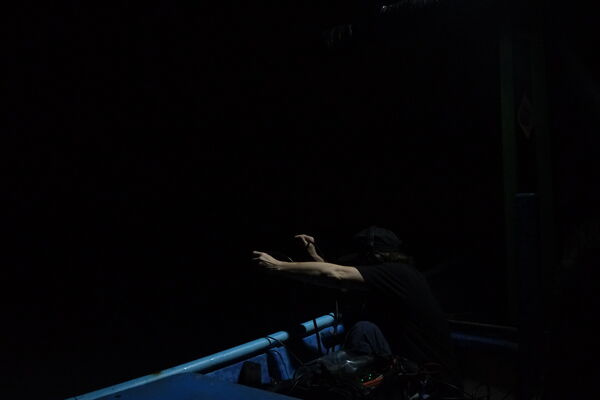 A dark room with a person cast in shadow on a stage that's lit up blue.