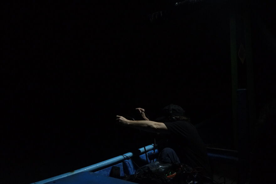 A dark room with a person cast in shadow on a stage that's lit up blue.
